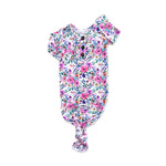 Vivienne Ruffle Baby Gown from Gigi & Max. Print is a pink and purple watercolor floral on a white background. 